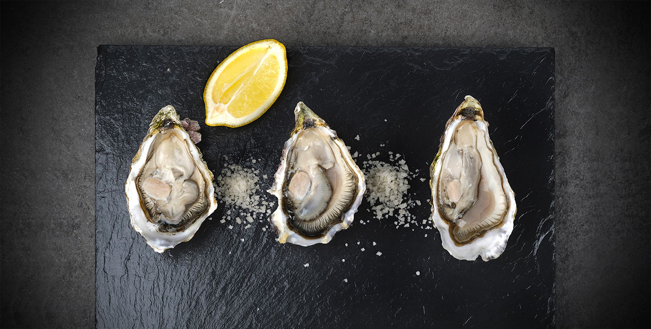 Trois huîtres et un citron sur une ardoise